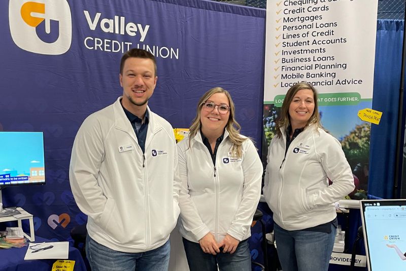 group of people standing in front of a Valley Credit Union banner